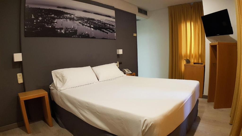 维戈维哥海滨酒店的卧室配有一张白色大床和电视。
