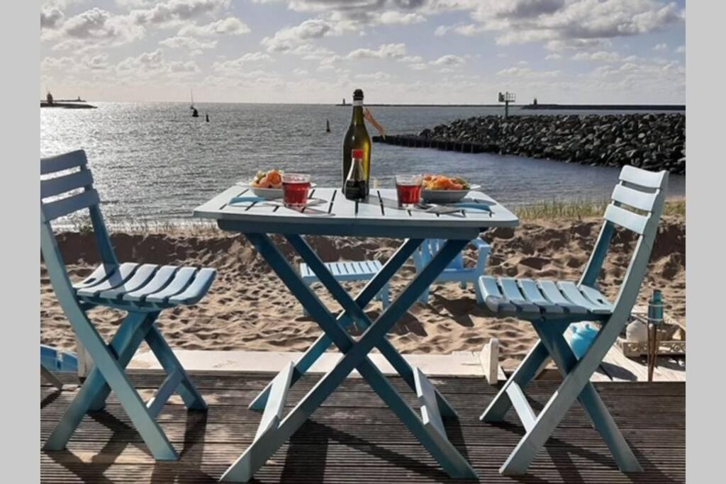 艾默伊登Beachhouse direct aan zee的一张野餐桌,配有一瓶葡萄酒和两把椅子