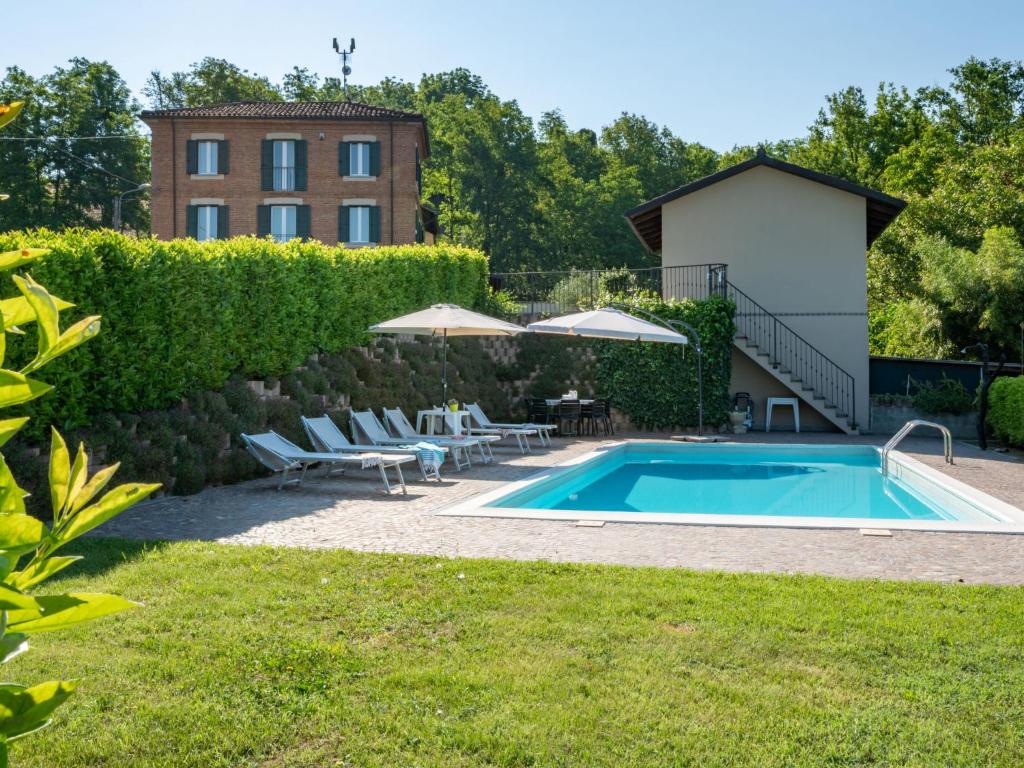 阿斯蒂Holiday Home Marmorito by Interhome的一座带椅子的庭院和一座建筑中的游泳池