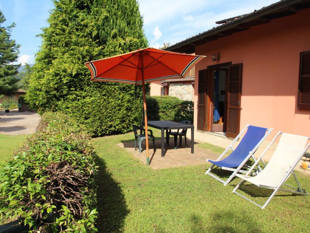 勒威诺Holiday Home Residenza Agrifoglio-12 by Interhome的一张桌子和两把椅子以及一把红色雨伞