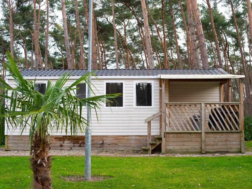 斯欣费尔德Holiday Home De Brenkberg-1的一座小白色小屋,位于一个树木繁茂的院子内