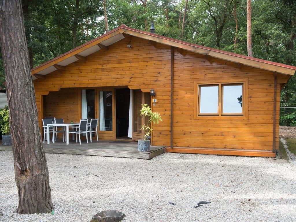 斯欣费尔德Holiday Home De Brenkberg-1的小木屋设有门廊,配有桌椅