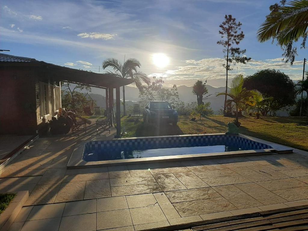 多明戈斯马丁斯Pousada Sítio Rústicu's的露台的游泳池,阳光在后面