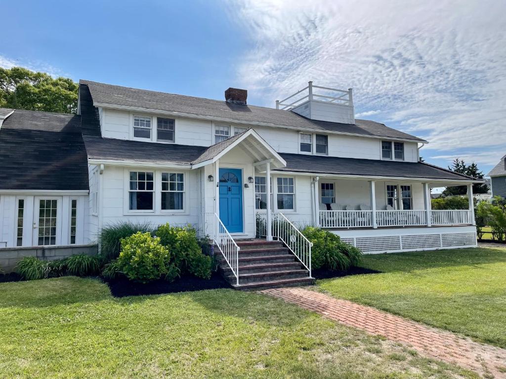 汉普顿贝斯Aria & Mare Hamptons的白色的房子,有蓝色的门和楼梯