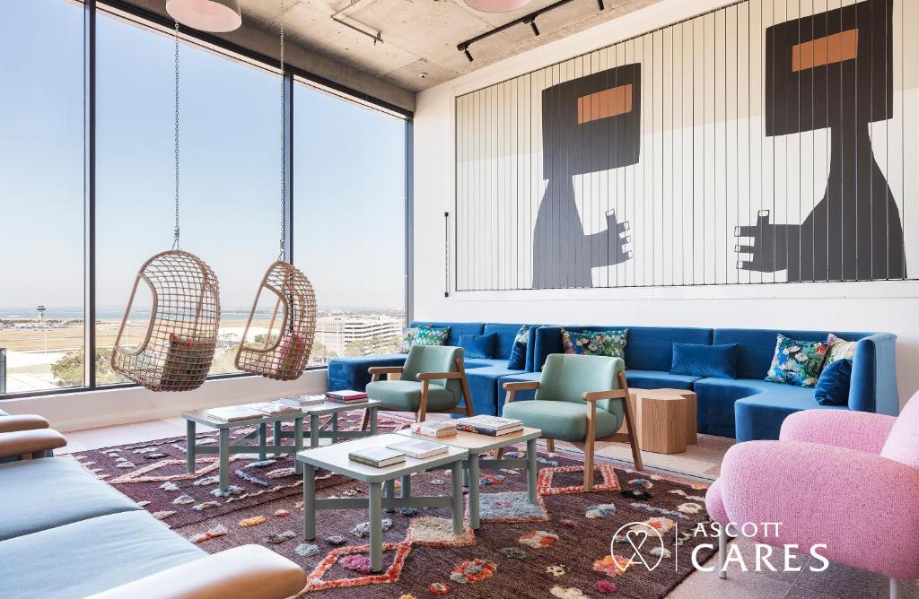 悉尼Citadines Connect Sydney Airport的客厅设有蓝色的沙发、桌子和窗户