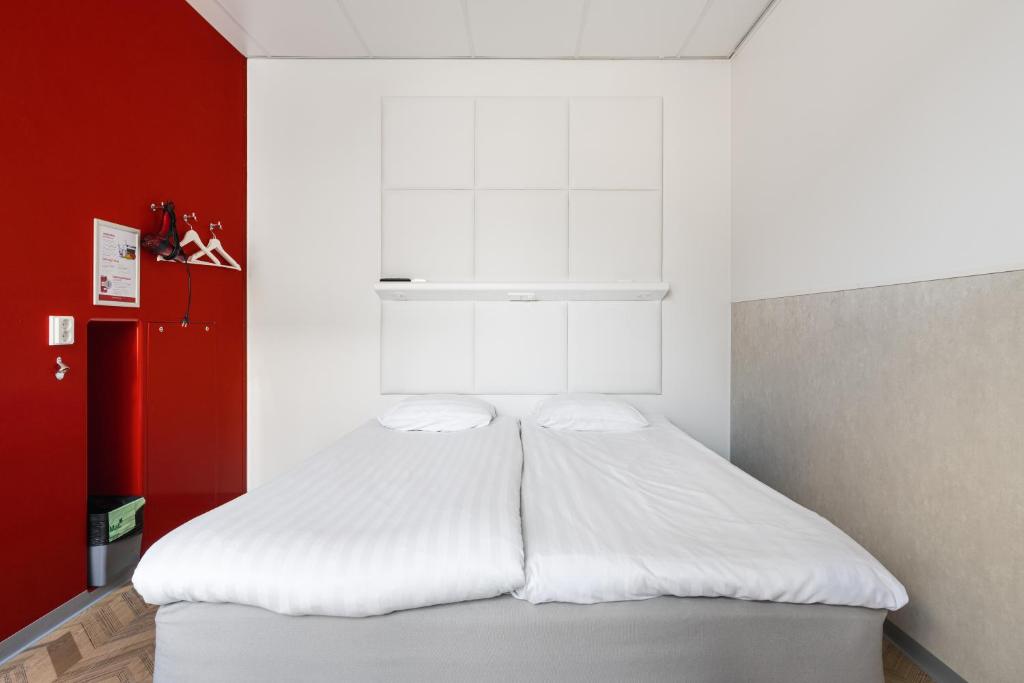 坦佩雷坦佩雷欧曼拉酒店的红色墙壁的房间里一张白色的床