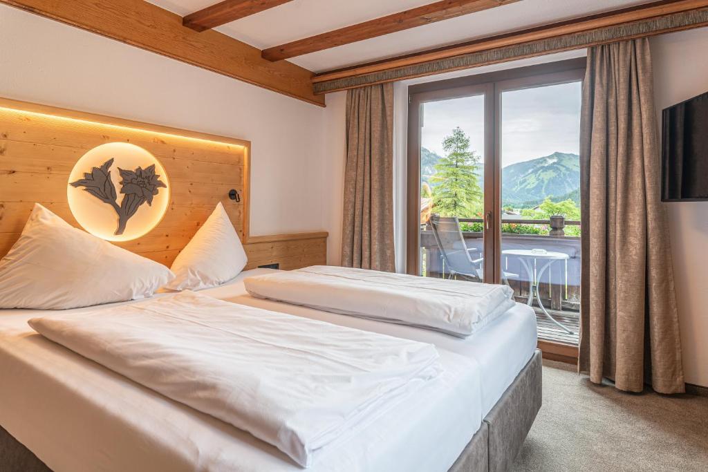 哈尔登熙Hotel Tyrol am Haldensee的一间卧室设有一张床和一个大窗户