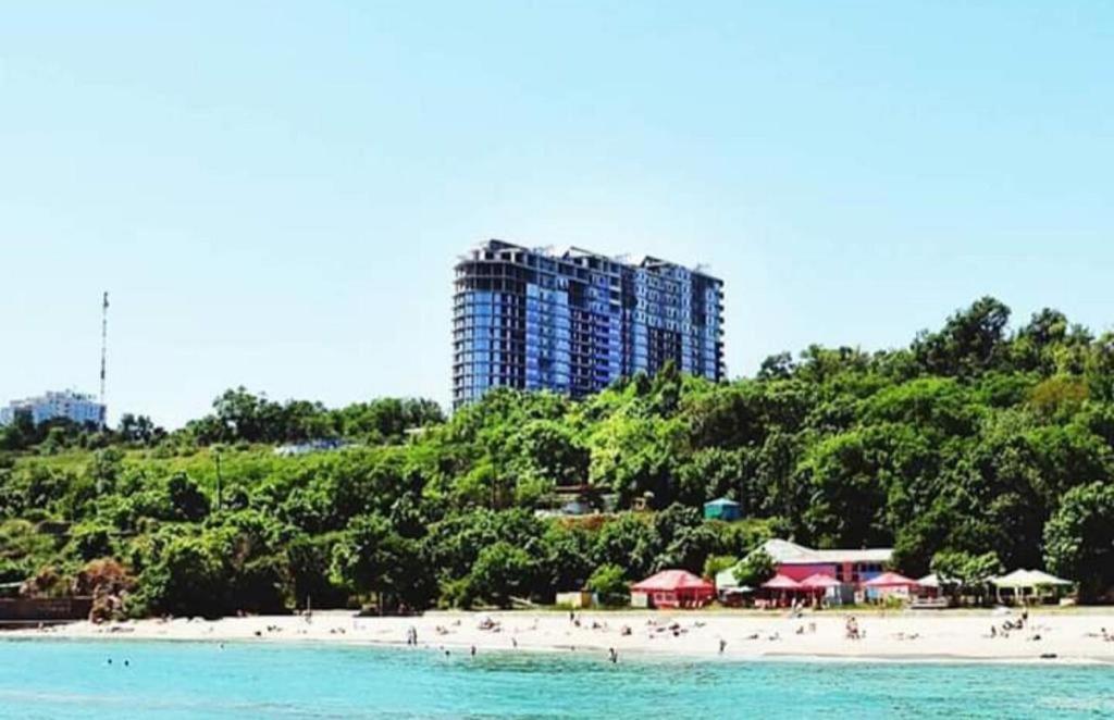 敖德萨Apart hotel Greenwood near Sea的一群人住在海滩上,有一座高大的建筑