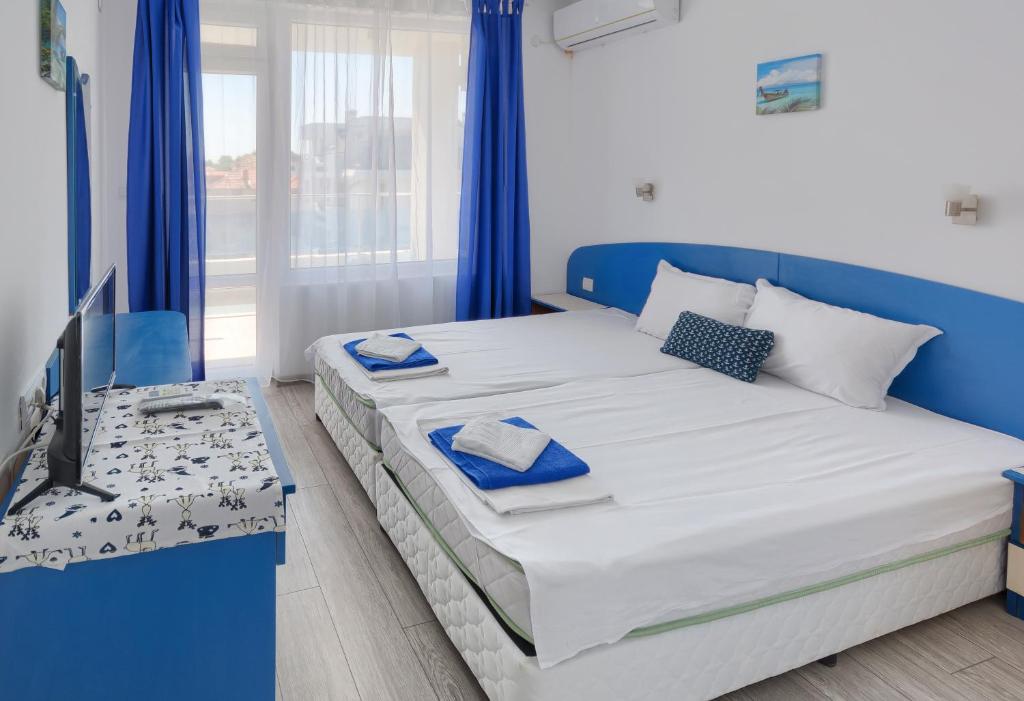 希典Hotel Siyanie Kiten的蓝色和白色的卧室设有1张床和1台电视