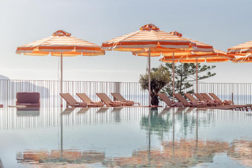 丰沙尔NEXT - by Savoy Signature的游泳池旁的游泳池配有椅子和遮阳伞