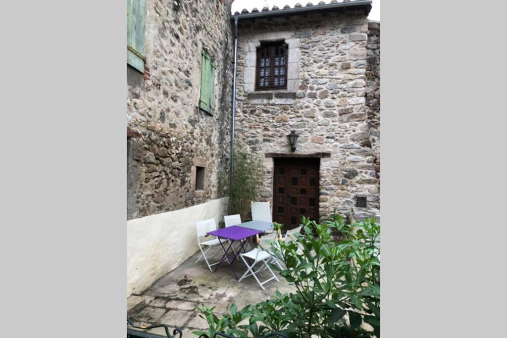 孔夫朗自由城Les Maisons du Conflent, maisons familiales en pierre au coeur des remparts的大楼前的紫色桌子和椅子