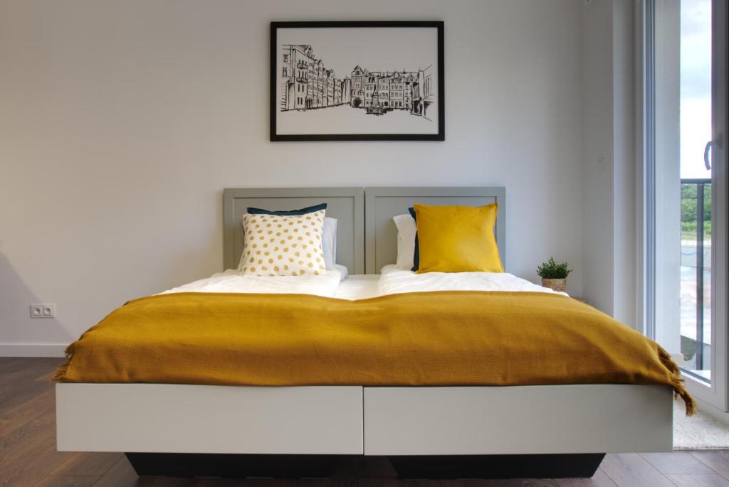 波兹南Essence Apartments Topaz的一间卧室配有一张带黄色枕头的大床
