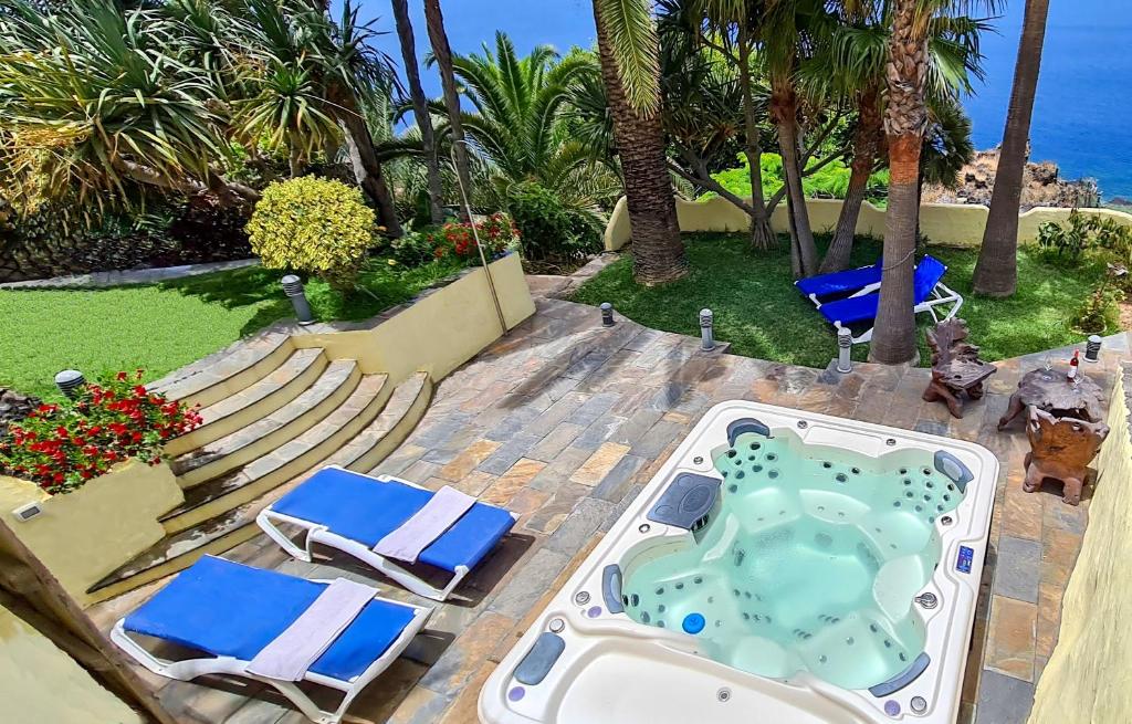 丰卡连特德拉帕尔马CASA LOS POLVEROS的一个带椅子的庭院和一个毗邻大海的热水浴缸