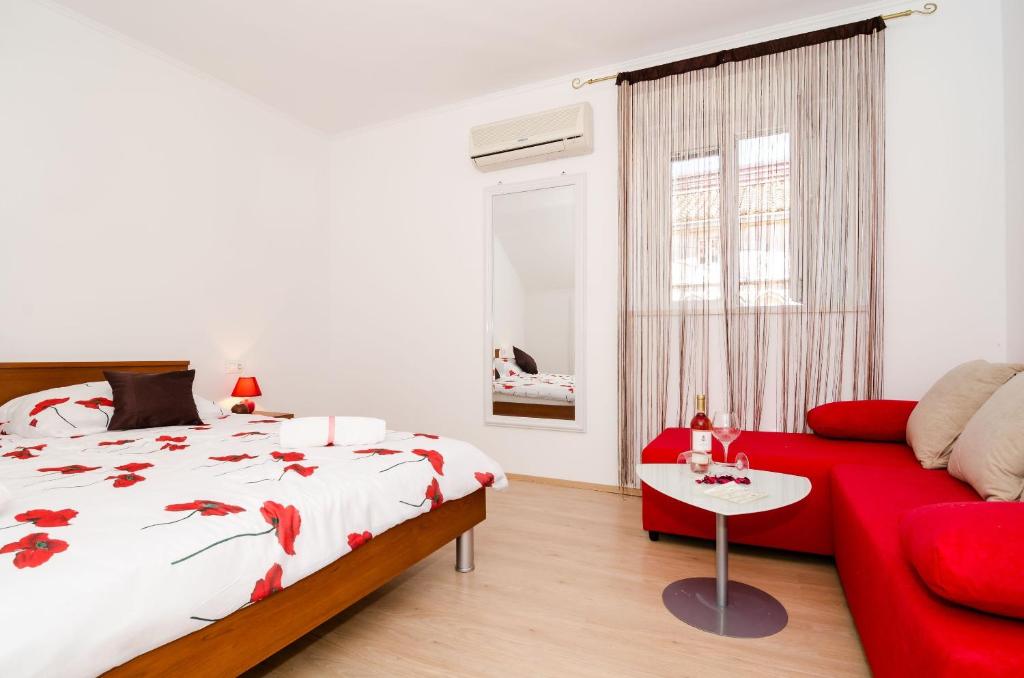 杜布罗夫尼克艾拉公寓酒店的一间卧室配有红色的床和红色的沙发