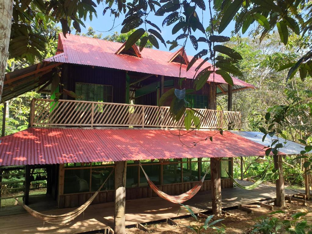Santa SofíaReserva Natural Tucuchira的房屋前方设有红色屋顶和吊床