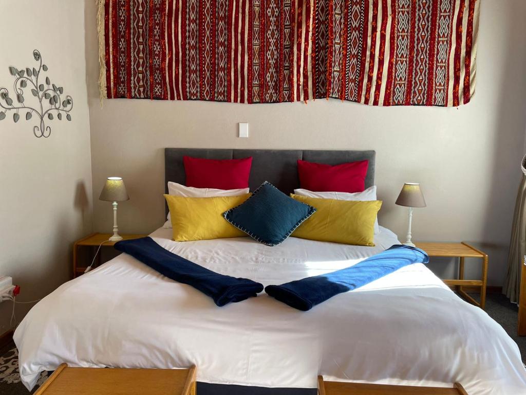 克拉伦斯Charmwood的卧室配有一张带彩色枕头的大型白色床。