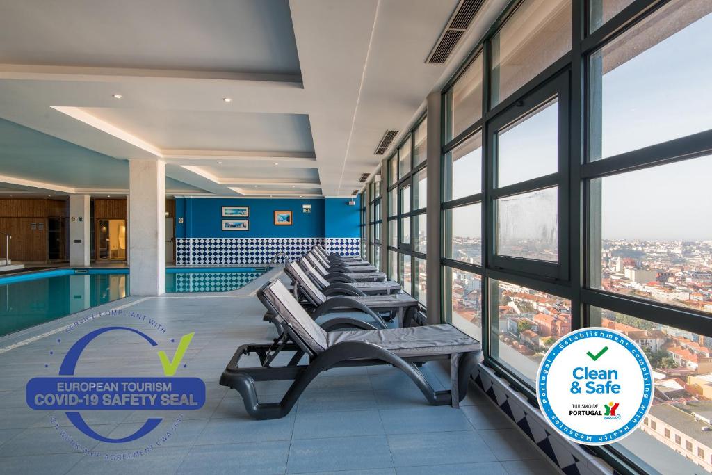 波尔图波尔图中心维拉家乐酒店的一座带游泳池的建筑里的一排长椅