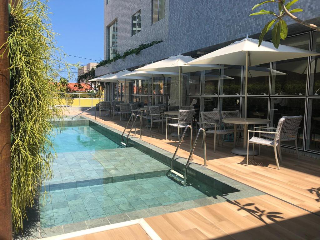 马塞约Flix Hotel的一个带桌椅和遮阳伞的游泳池