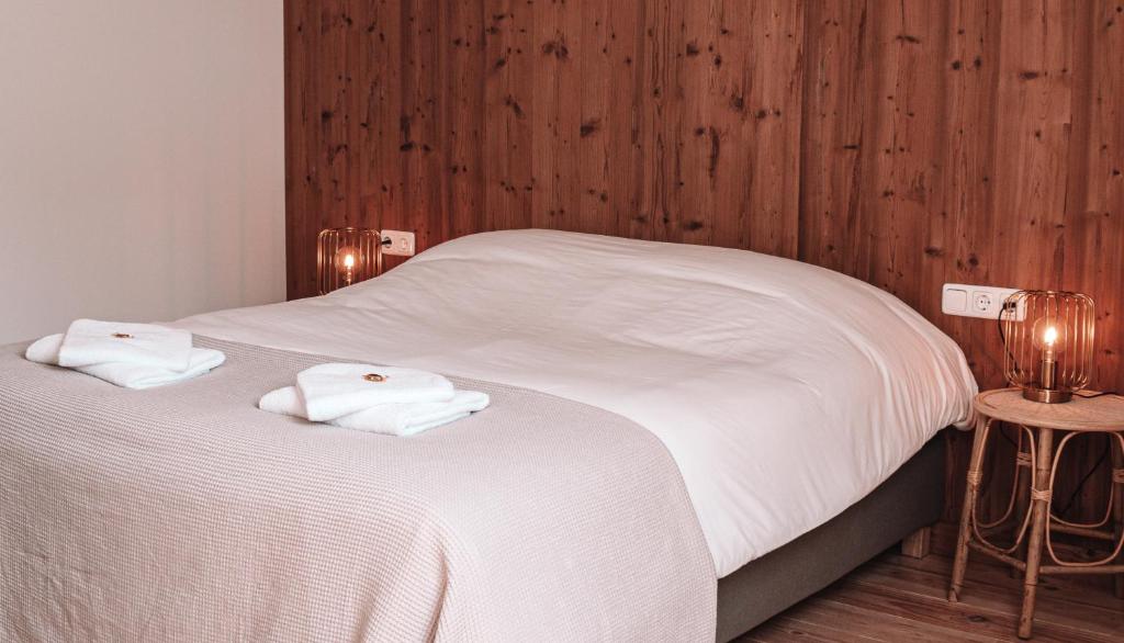 斯内克Friese Hoeve Sneek的一间卧室配有两张带白色床单和木墙的床。