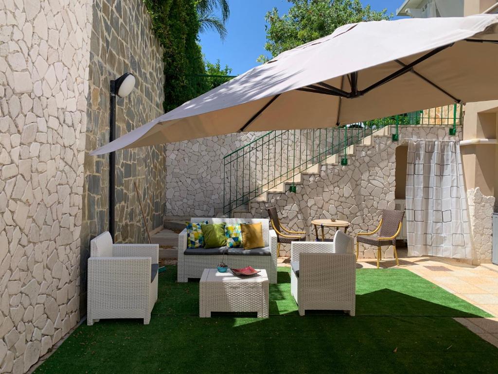 波利科罗Appartamento in Villa a Policoro的一个带椅子和白色遮阳伞的庭院