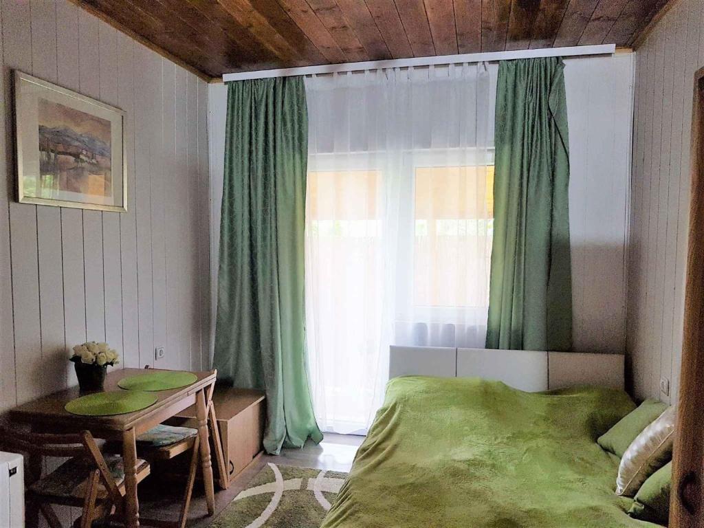鲍洛托瑙考利Holiday Homes in Balatonakali 37748的一间卧室设有床铺和一个带绿色窗帘的窗户。