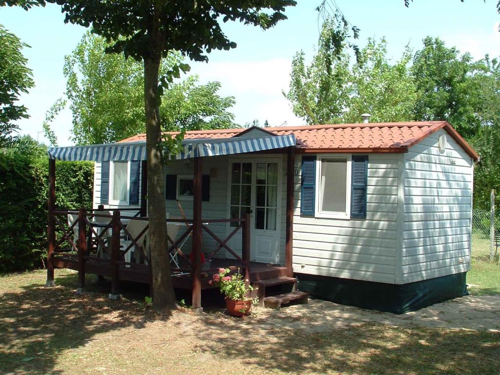 卡瓦利诺Mobilehomes in Cavallino-Treporti 33773的一个小棚子,有门廊和一棵树