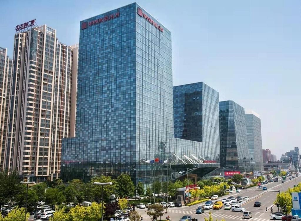 廊坊廊坊富力万达嘉华酒店的一座高大的玻璃建筑,有汽车在城市里