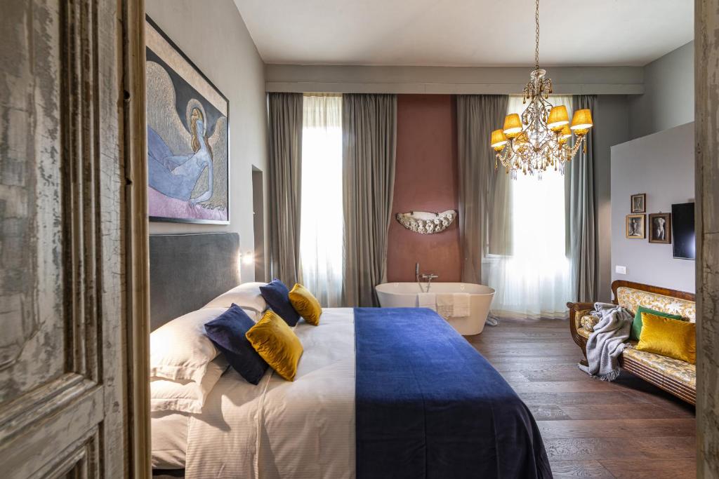 佛罗伦萨波迪赛丽酒店的一间卧室配有一张床、一个浴缸和一个吊灯。