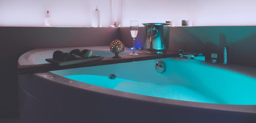坎波马里诺Le Dimore del Borgo - Room & Breakfast的浴室里设有蓝色的浴缸,备有一杯葡萄酒