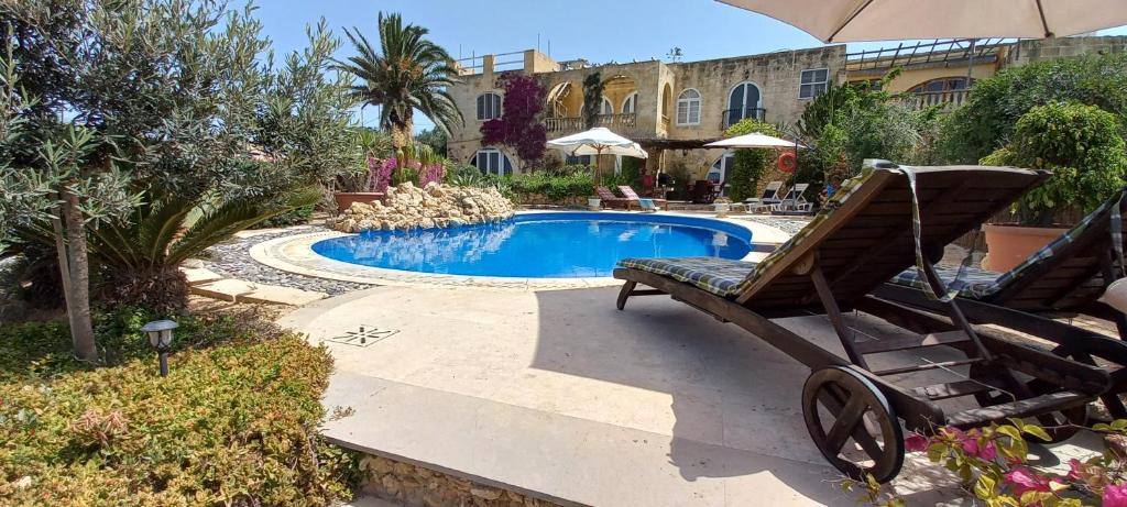 圣劳伦斯Dar Ta' Xmun - idyllic farmhouse with pool, garden, seaview & sunset的一个带椅子和遮阳伞的游泳池
