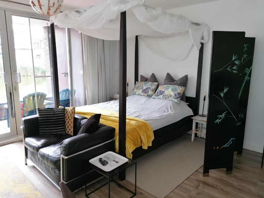 阿姆斯特丹The Water Studio的一间卧室配有四柱床和沙发