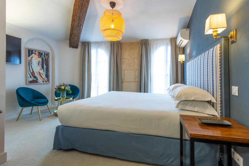 阿尔勒Hôtel Le Relais de Poste Arles Centre Historique的一间卧室配有一张大床、一张桌子和一张书桌
