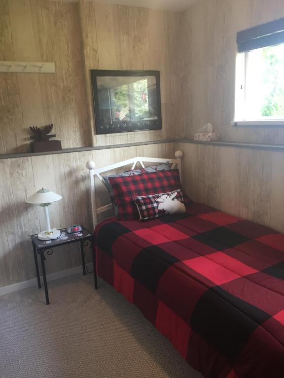 史密瑟斯斯尔弗恩湖畔小路住宿加早餐酒店的一间卧室配有一张带红色和黑色毯子的床