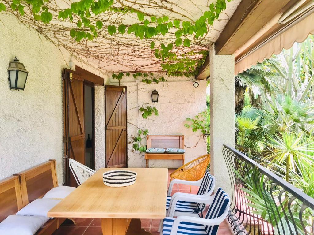 罗达德瓦拉Casa mediterránea con gran jardín y piscina a 500 m de la playa的阳台上配有一张木桌和椅子,
