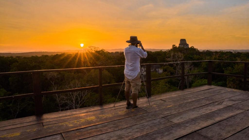 蒂卡尔蒂卡尔丛林小屋酒店的一位在大峡谷拍摄日落景象的人