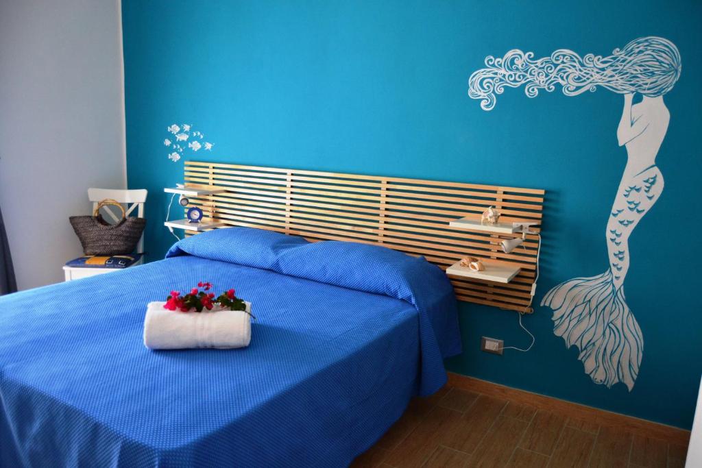 圣维托罗卡波B&B Vivere il Mare的一间卧室配有蓝色的床,床上插着花