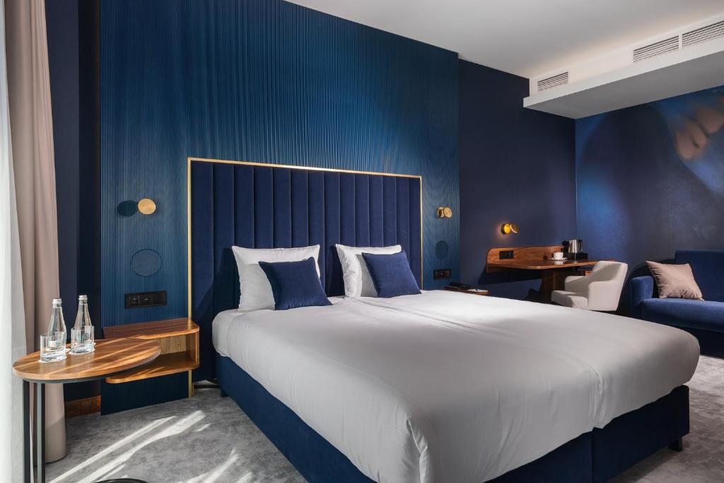 格丁尼亚My Story Gdynia Hotel的一间卧室设有一张大床和蓝色的墙壁