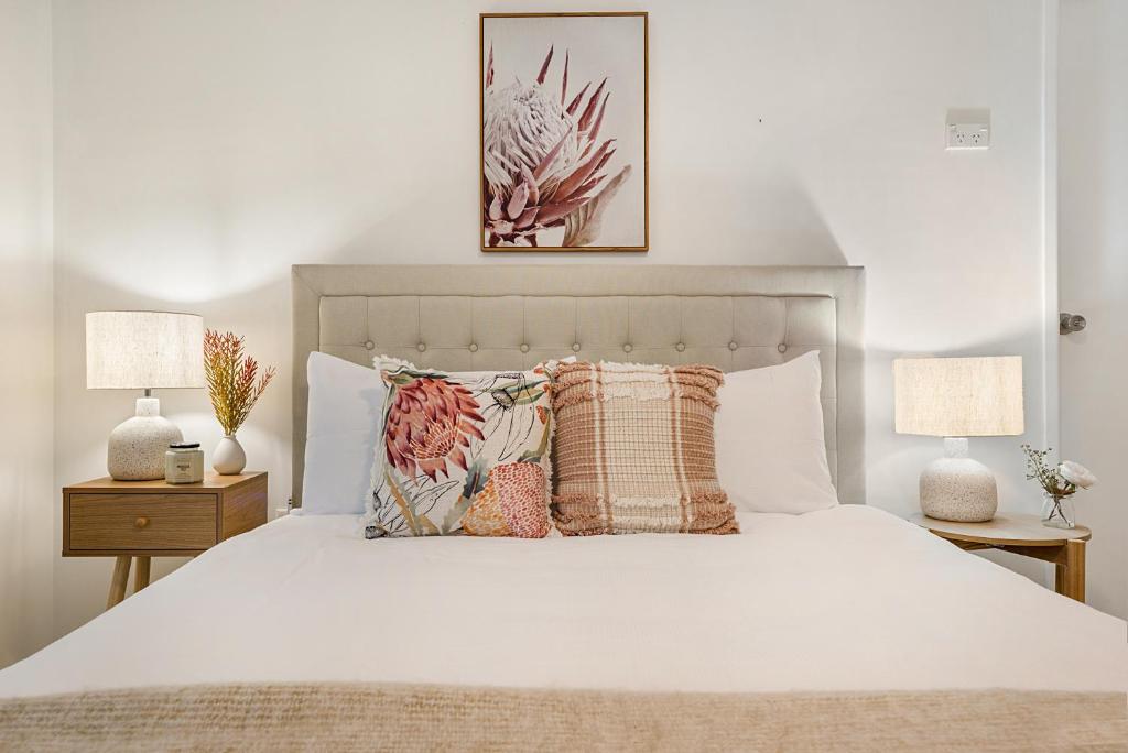 卡伦德拉Spacious Family Beach House的卧室配有带枕头和两盏灯的白色床。