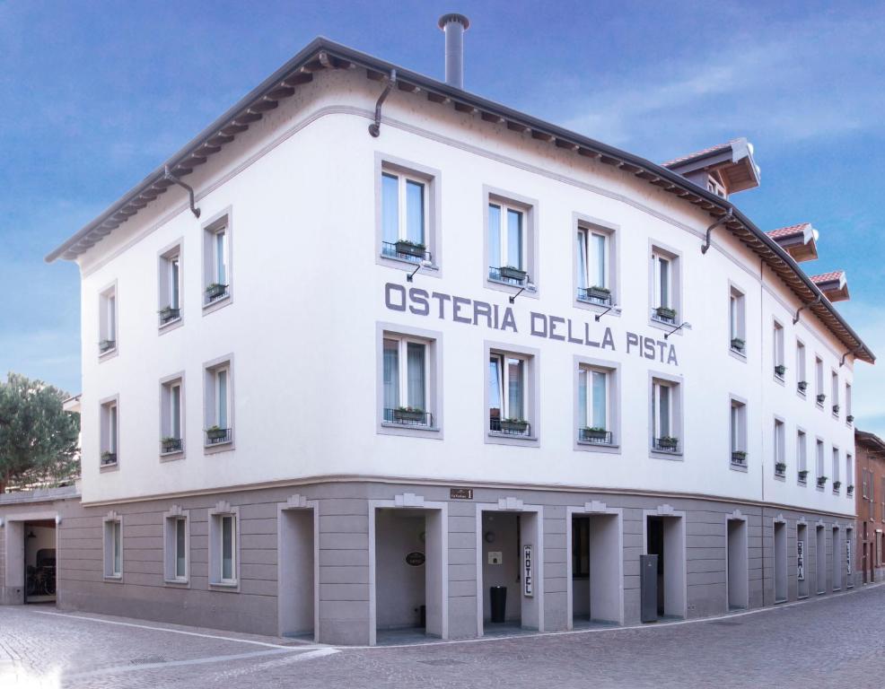 卡索雷特塞皮翁Hotel Osteria della Pista dal 1875的白色的建筑,带有古怪的花纹反射