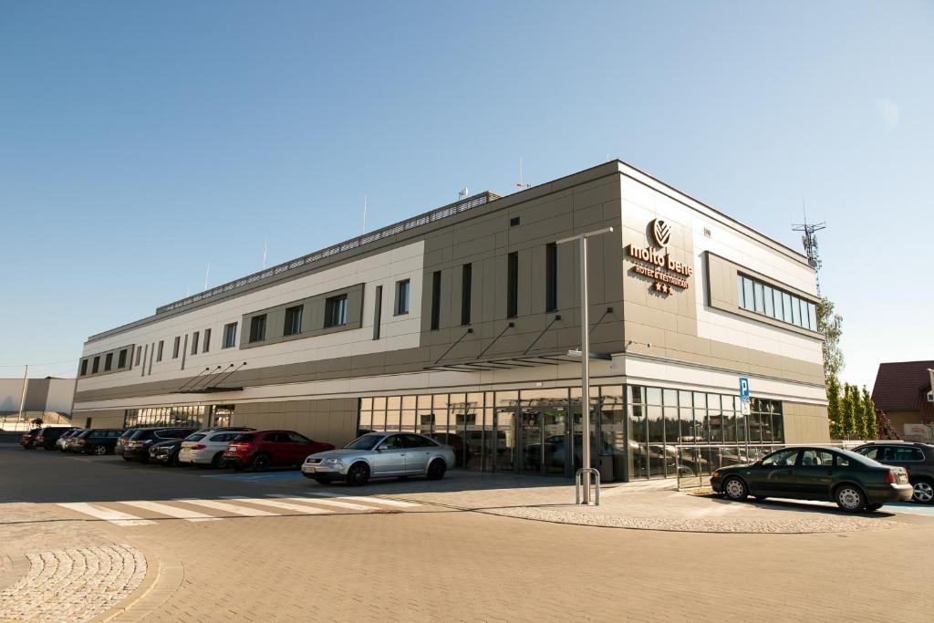 SkórczMolto Bene Hotel & Restaurant的停车场内停放汽车的大型建筑