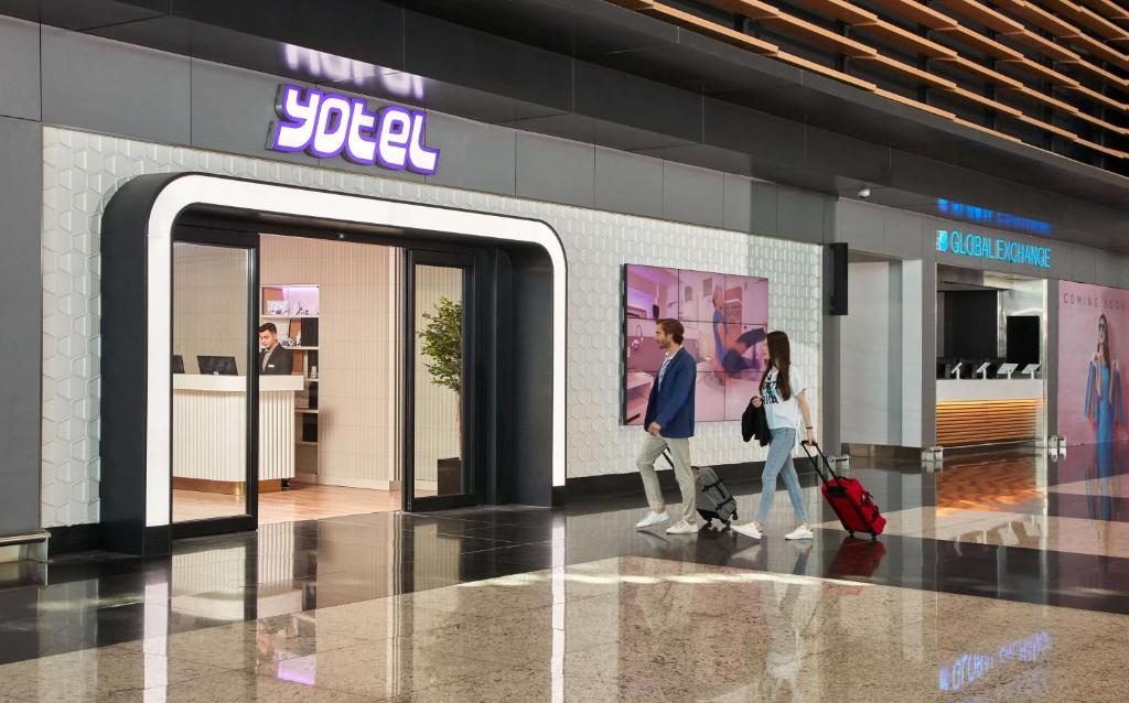 伊斯坦布尔YOTEL Istanbul Airport, City Entrance的两个人在商店里走过门