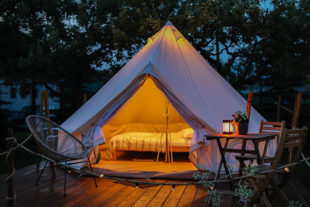 TeşilaValea Doftanei Glamping的帐篷,配有一张位于甲板上的床铺和一张桌子