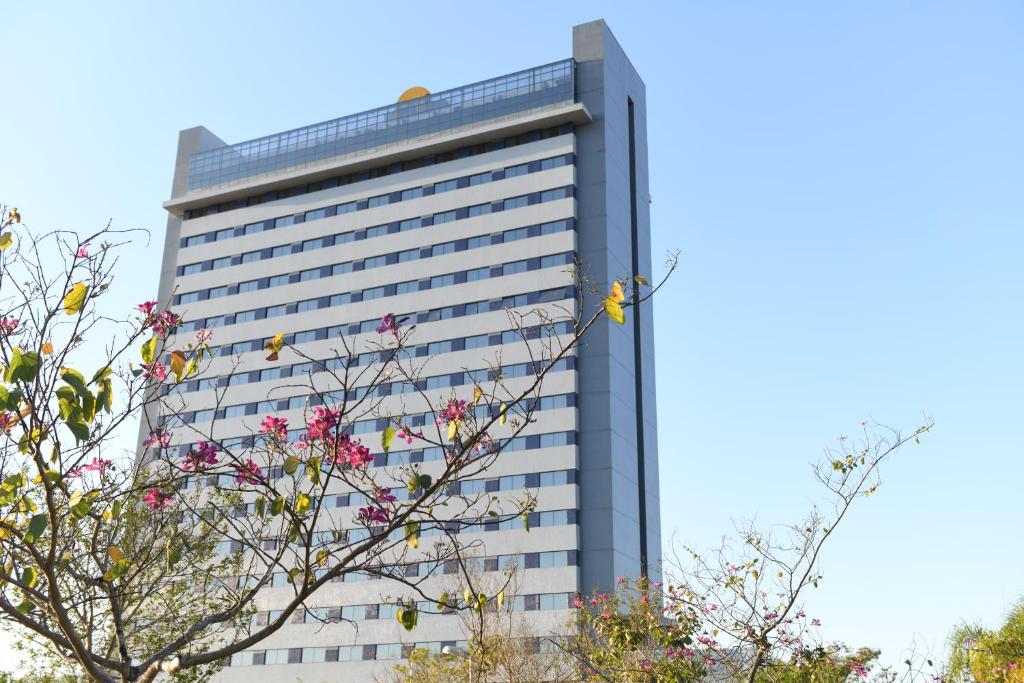 阿帕雷西达赖尼亚巴西酒店的一座高大的建筑,前面有粉红色的花朵