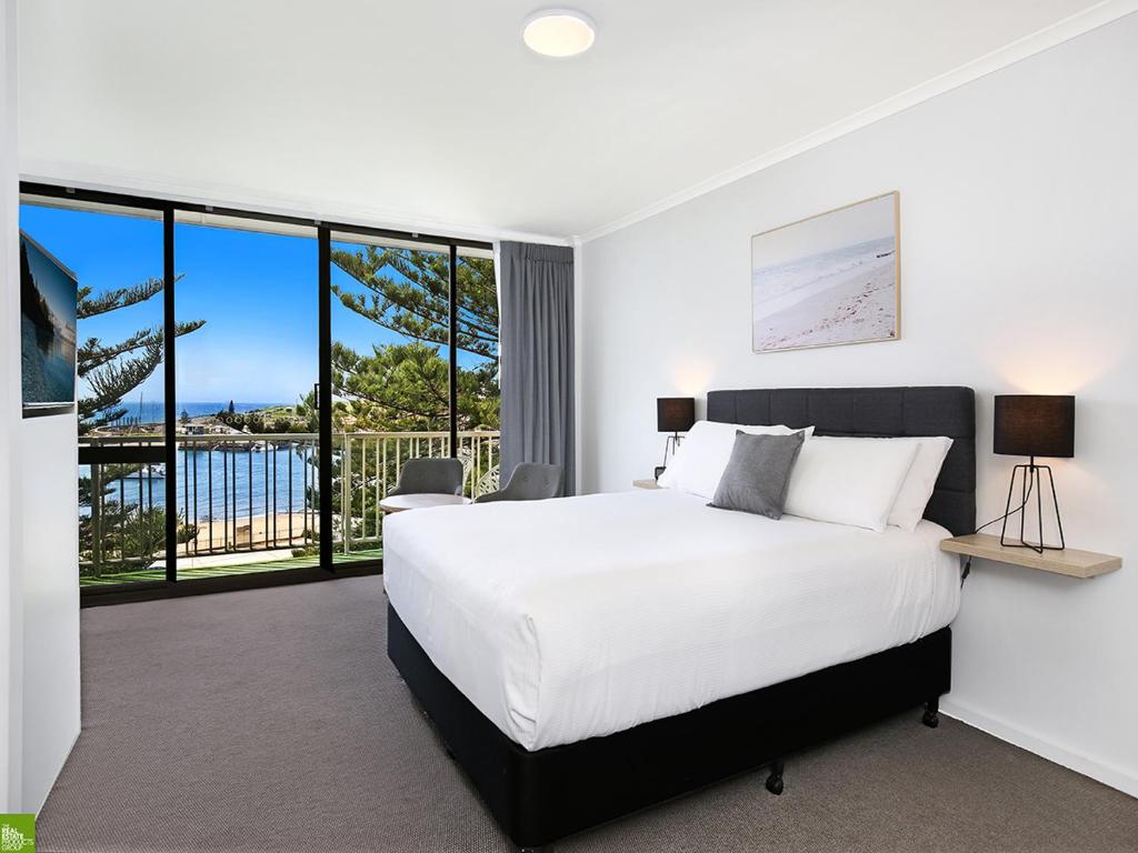 卧龙岗游艇码头汽车旅馆的卧室设有一张白色大床和大窗户