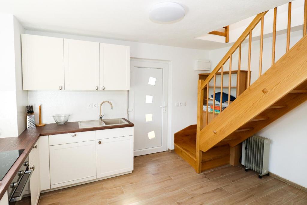 特尔日奇Apartment Organic Farm Hvadnik的厨房配有白色橱柜和木制楼梯。