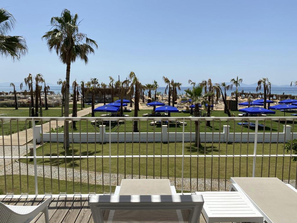 艾瓦勒克Ayvalık Sea Resort的海滩景,设有野餐桌和棕榈树