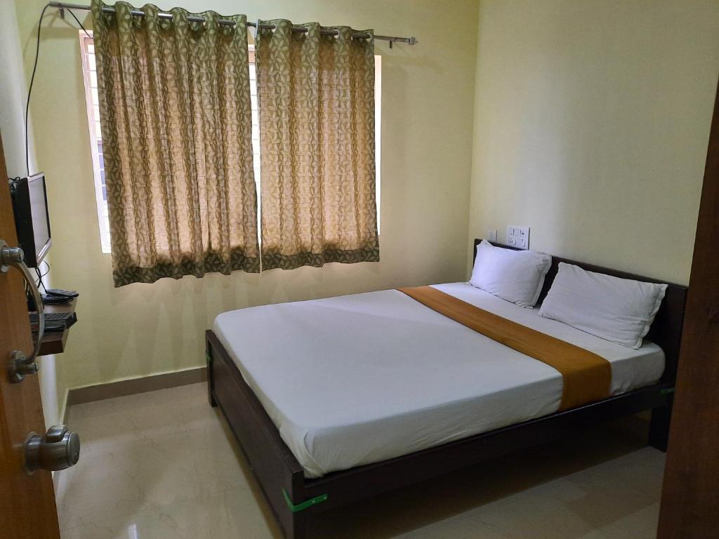 迈索尔Royal Suvarna Comforts的一间卧室设有一张大床和窗户