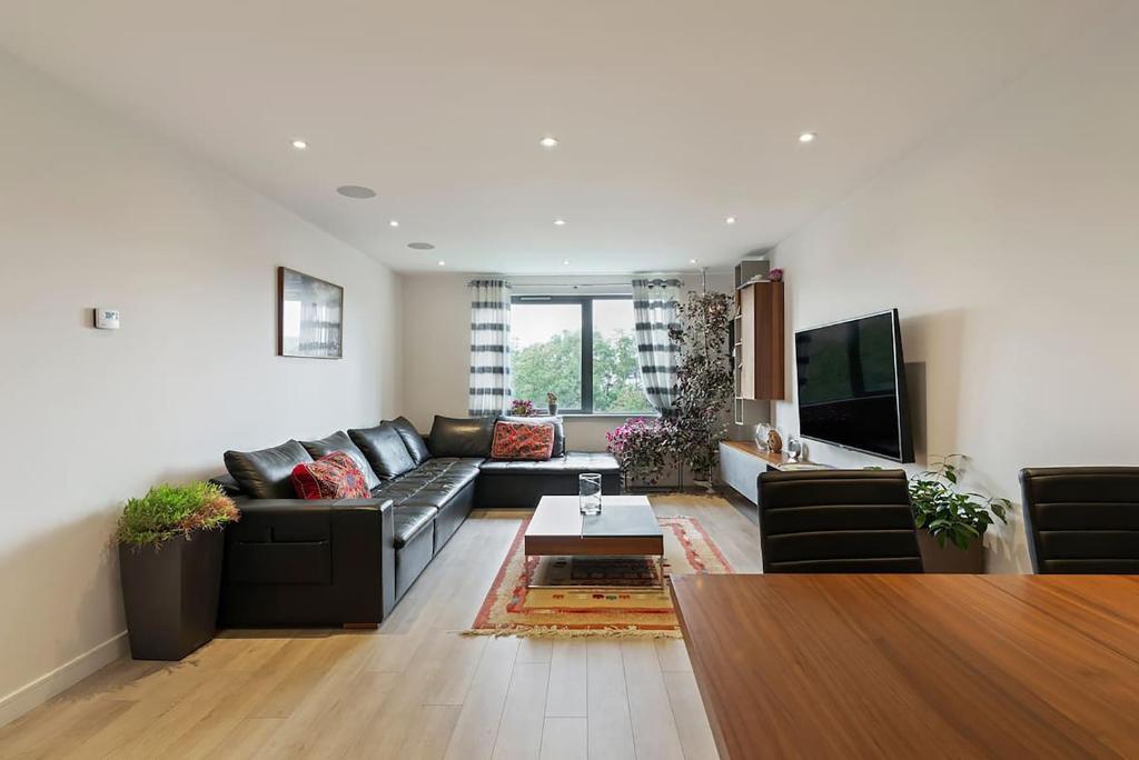 New Southgate1-Bed Spacious Flat, North London, 15 Minutes to Central的客厅配有黑色沙发和电视