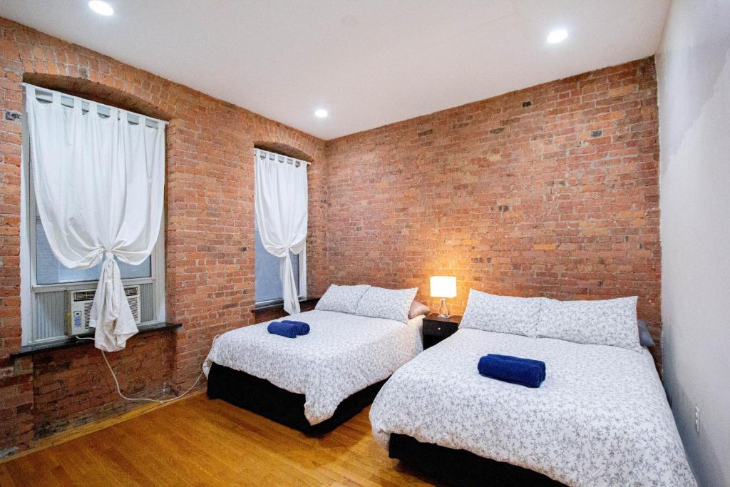 纽约一卧室超级公寓的一间卧室设有两张床和砖墙