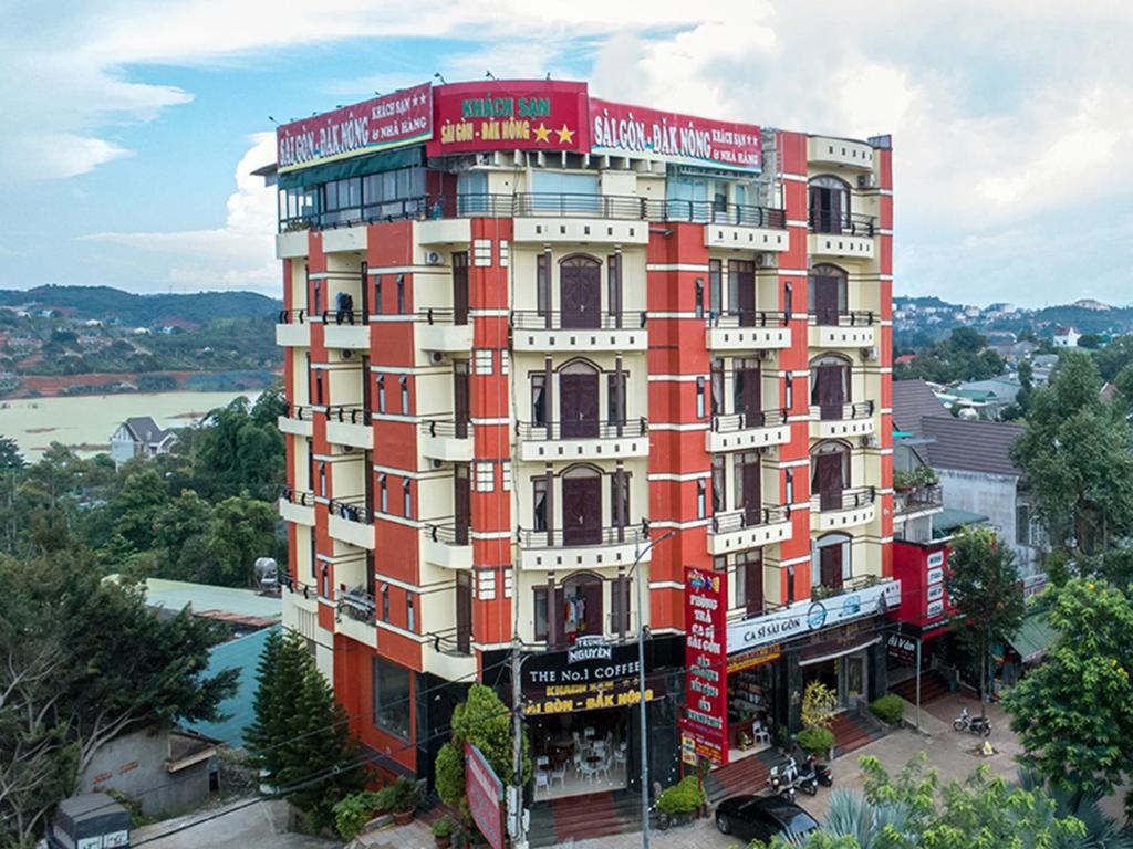 Gia Nghĩa西贡达农酒店的一座红白色的建筑,后面有一条河流